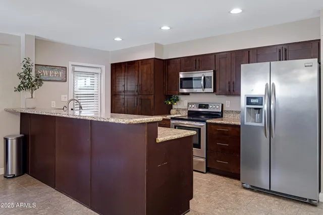 a kitchen with granite countertop stainless steel appliances a refrigerator and a counter top space