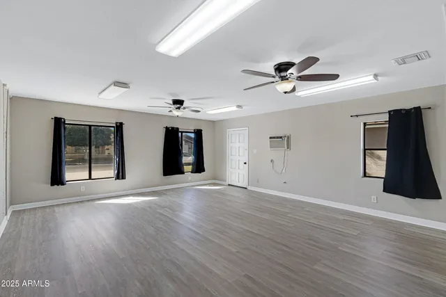 a view of an empty room with window and wooden floor