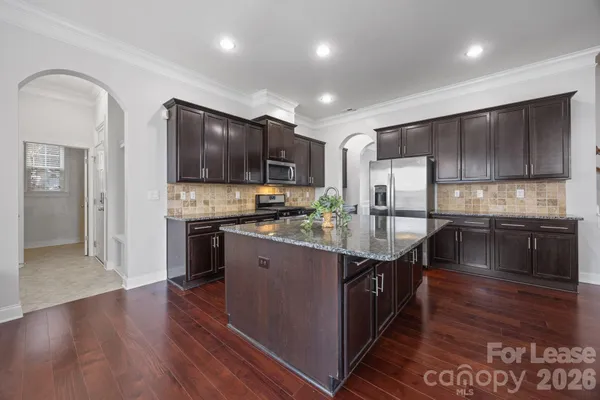 a kitchen with stainless steel appliances granite countertop a refrigerator a stove and a sink with wooden cabinets