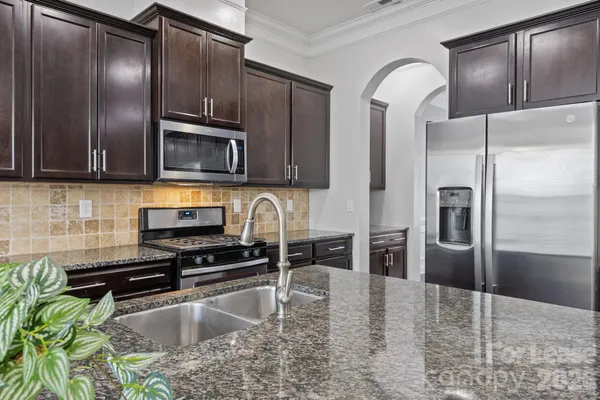 a kitchen with granite countertop stainless steel appliances a sink stove top oven and cabinets