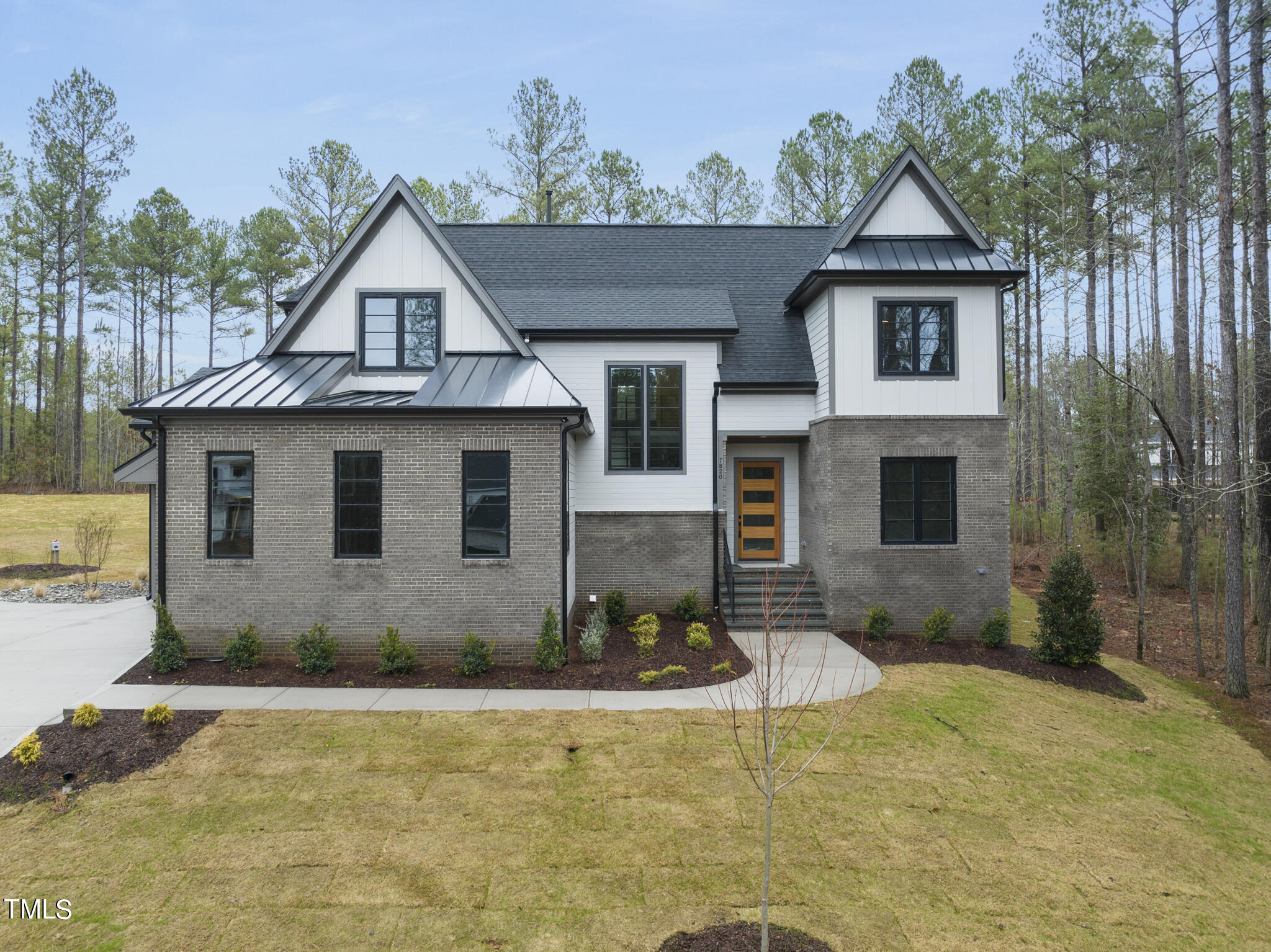 a front view of a house with yard and trees in the background