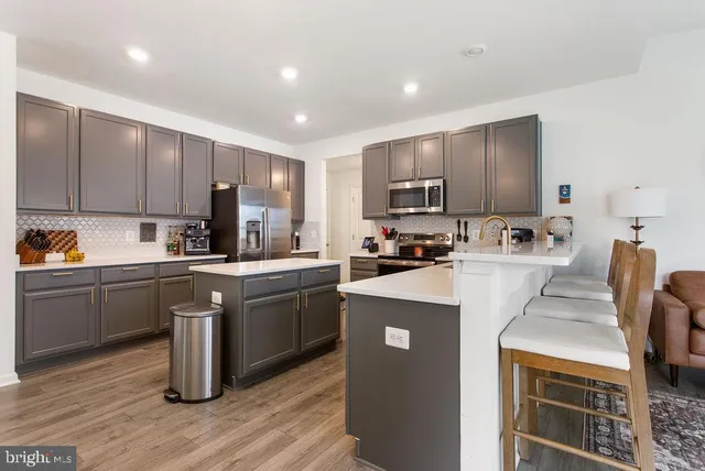 a kitchen with stainless steel appliances granite countertop a stove top oven a sink refrigerator and cabinets