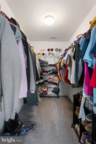 a view of walk in closet with clothes and shoes