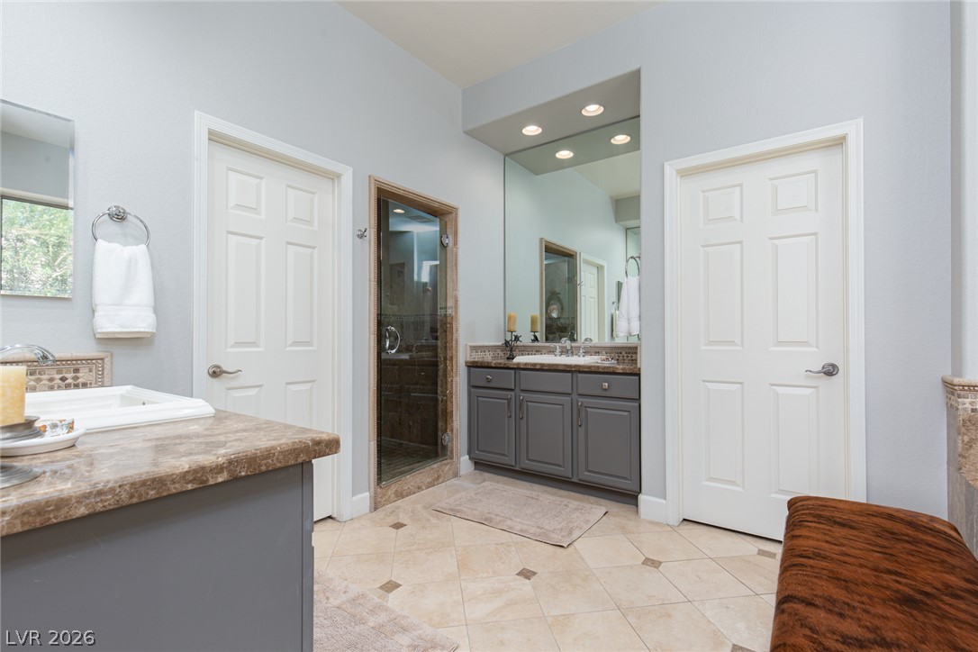 22 Douglas Grove Road Henderson, NV 89052 - Photo 36 of 72 Functional primary bathroom features dual vanity areas and a glass-enclosed shower.