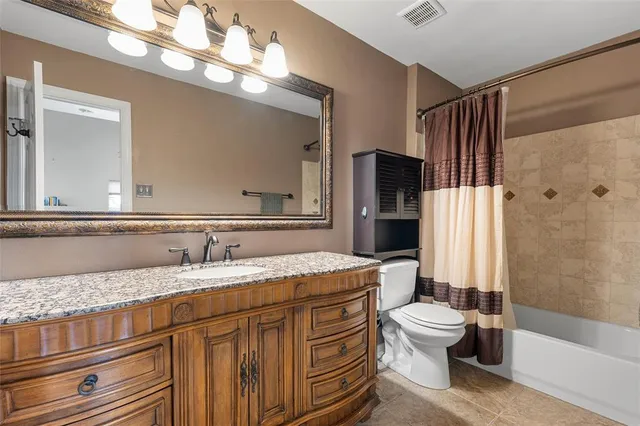 a bathroom with a granite countertop double vanity sink mirror and toilet