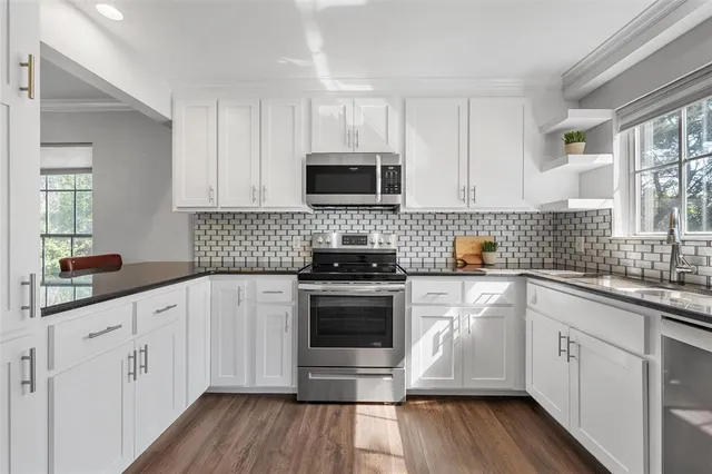 a kitchen with cabinets stainless steel appliances a sink and wooden floor