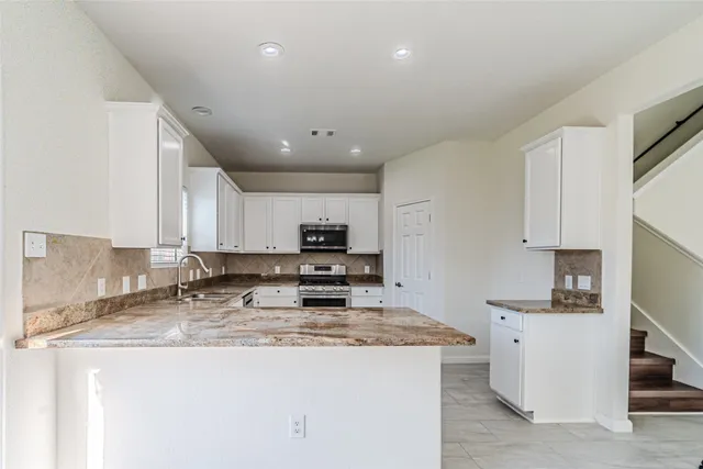 a kitchen with kitchen island granite countertop a sink a stove and cabinets