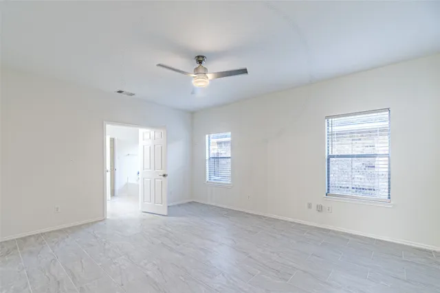 an empty room with windows and ceiling fan