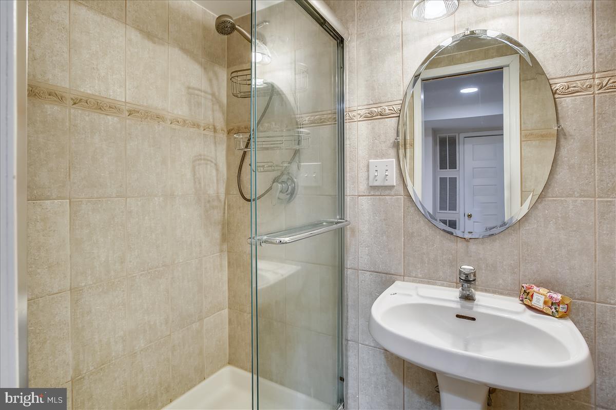 4664 Reservoir Road Northwest Washington, DC 20007 - Photo 47 of 60 a bathroom with a sink a mirror a vanity and shower