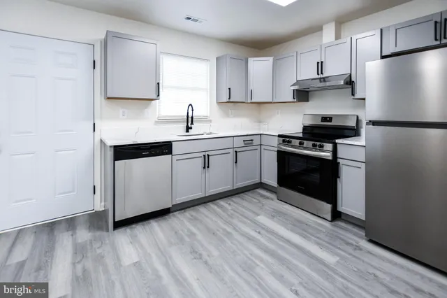 a kitchen with stainless steel appliances granite countertop a stove a sink and white cabinets
