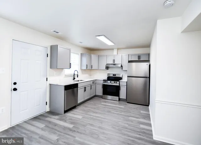 a kitchen with stainless steel appliances a refrigerator sink and white cabinets