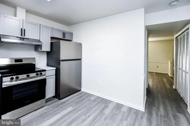 a kitchen with a refrigerator stove and wooden floor