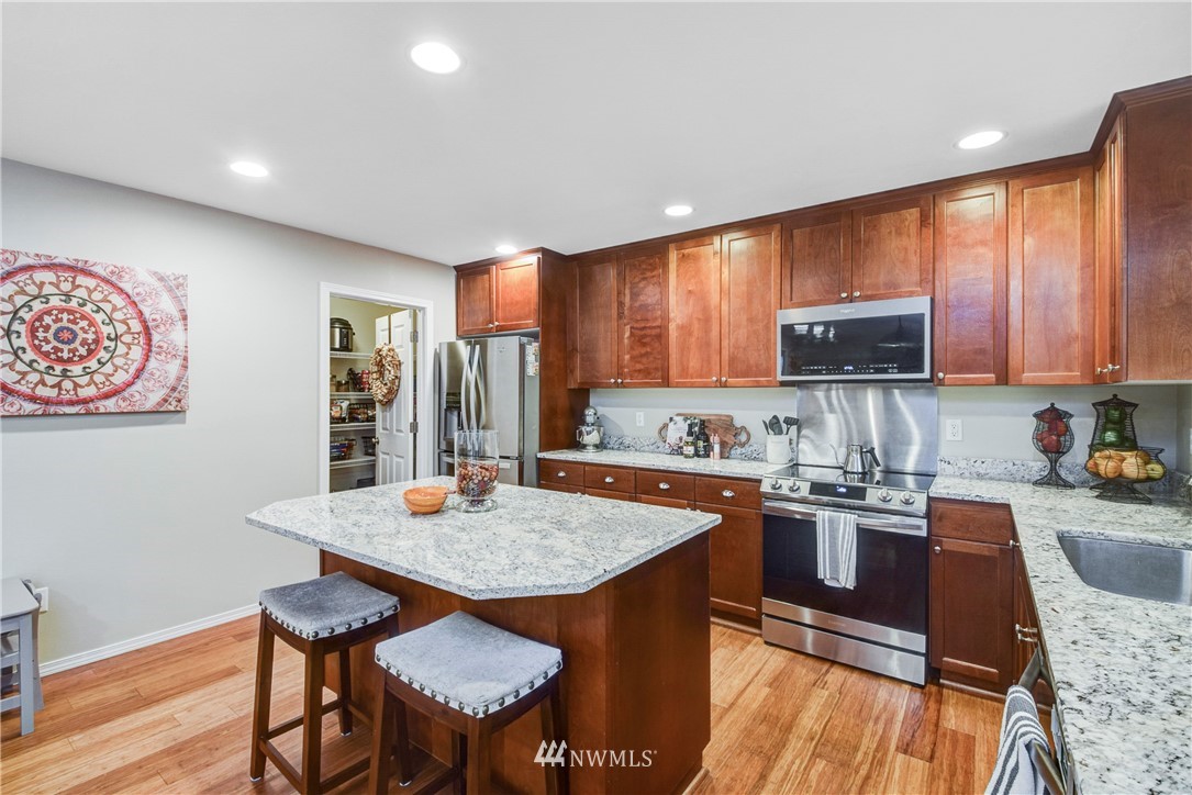 2405 194th Street Southeast Bothell, WA 98012 - Photo 11 of 28 a kitchen with stainless steel appliances granite countertop a stove top oven a sink a stove a dining table and chairs