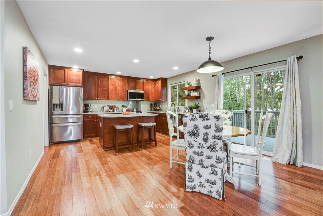 2405 194th Street Southeast Bothell, WA 98012 - Photo 14 of 28 a kitchen with stainless steel appliances granite countertop a refrigerator a stove top oven a sink dishwasher and wooden cabinets with wooden floor