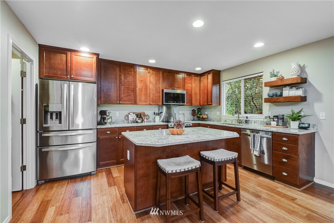 2405 194th Street Southeast Bothell, WA 98012 - Photo 9 of 28 a kitchen with stainless steel appliances granite countertop a refrigerator a sink dishwasher a stove and white countertops with wooden floor