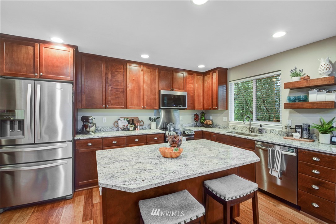 2405 194th Street Southeast Bothell, WA 98012 - Photo 10 of 28 a kitchen with stainless steel appliances granite countertop a refrigerator a sink dishwasher a stove a dining table and chairs with wooden floor