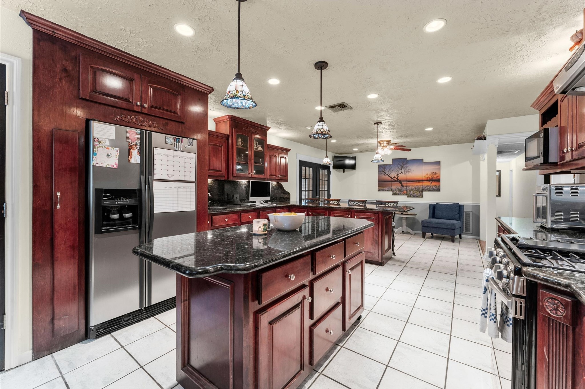 22634 Park Road Tomball, TX 77377 - Photo 10 of 29 Spacious kitchen featuring rich wood cabinetry, a sleek black granite island, and modern stainless steel appliances, perfect for culinary enthusiasts.