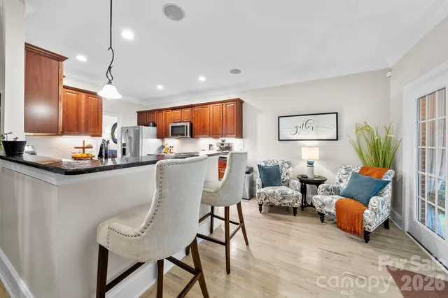 a living room with stainless steel appliances kitchen island granite countertop furniture and a dining table with wooden floor
