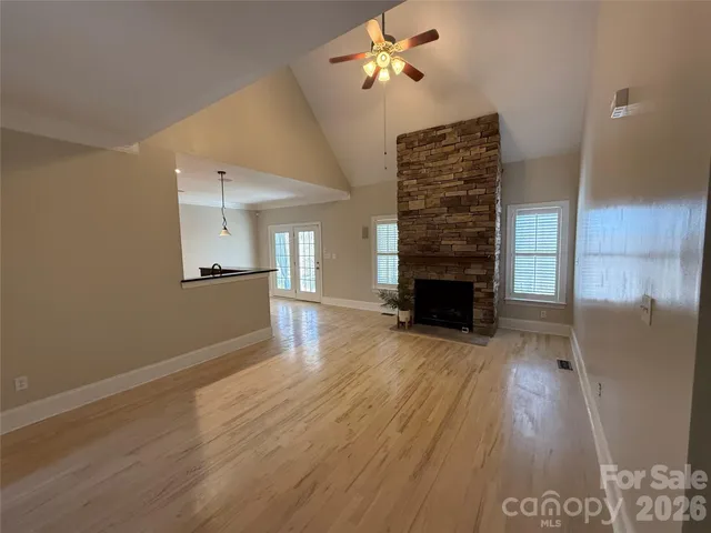 a view of a livingroom with wooden floor a ceiling fan and staircase