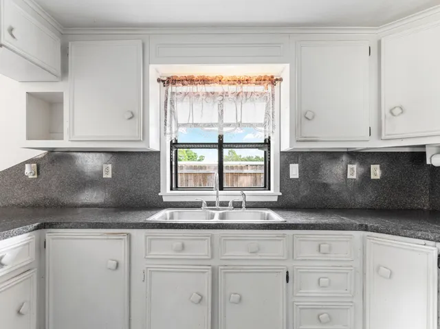 a kitchen with granite countertop white cabinets and a window