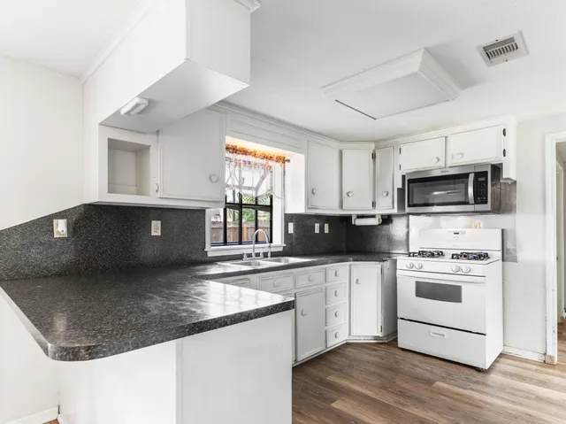 a kitchen with stainless steel appliances granite countertop a sink a stove top oven a counter space and cabinets
