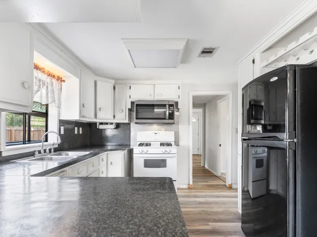 a kitchen with stainless steel appliances kitchen island granite countertop a refrigerator and a stove top oven