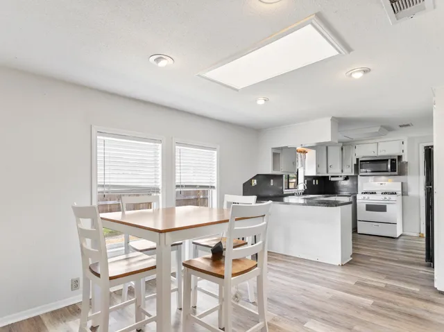 a kitchen with stainless steel appliances kitchen island granite countertop a stove a sink a dining table and chairs