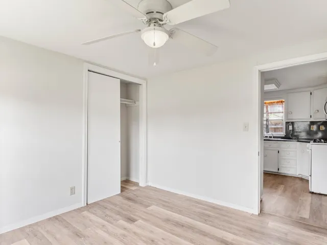 a view of a kitchen and a ceiling fan wooden floor and cabinets