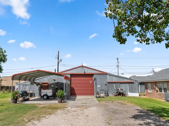 a view of a big house with table and chairs under an umbrella