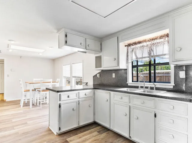 a kitchen with white cabinets and sink