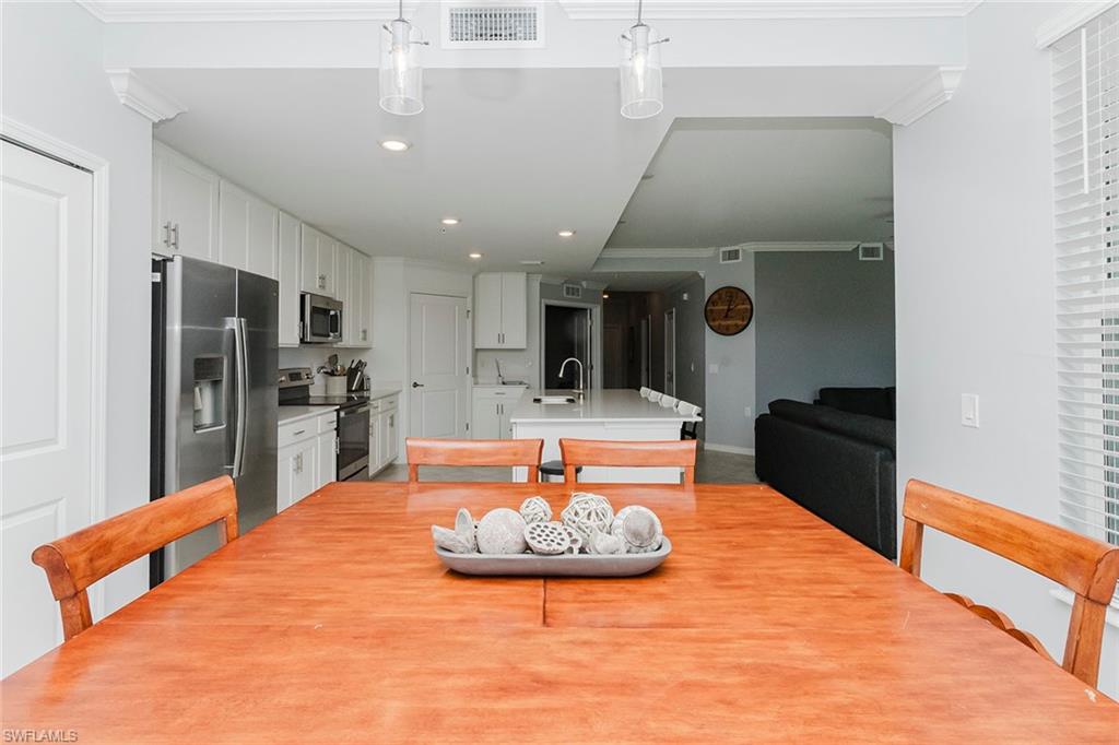 6082 National Blvd Avenue, Unit 115 Immokalee, FL 34142 - Photo 15 of 50 a kitchen with stainless steel appliances kitchen island granite countertop a table chairs in it and wooden floors