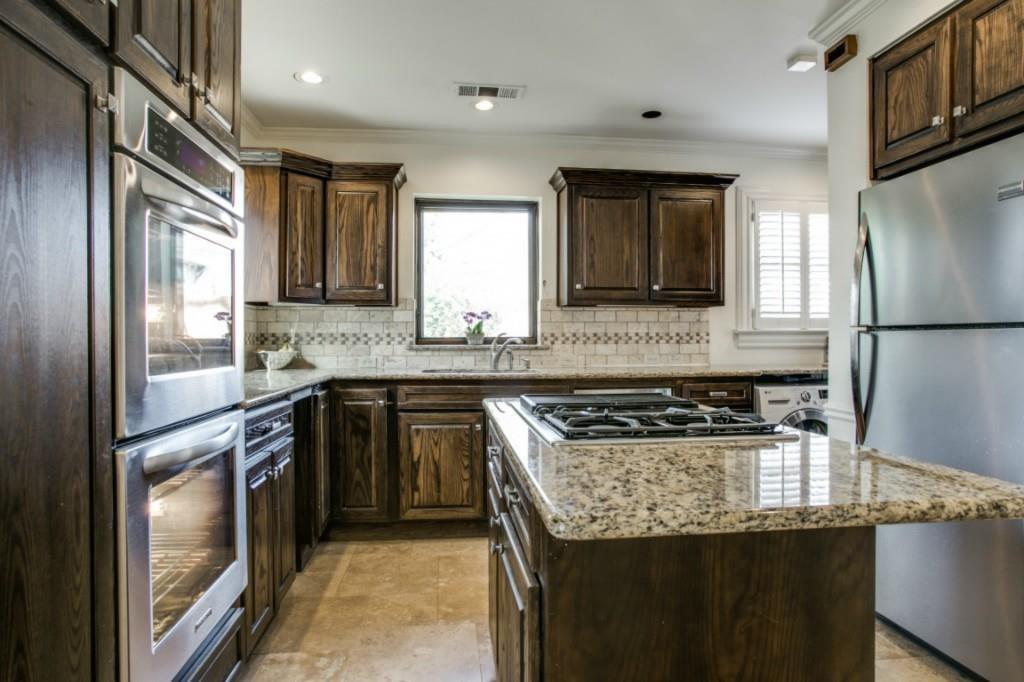 5419 Merrimac Avenue Dallas, TX 75206 - Photo 12 of 17 Kitchen featuring wood cabinetry, stainless steel appliances, a center island with a cooktop, stone countertops, and a subway tile backsplash