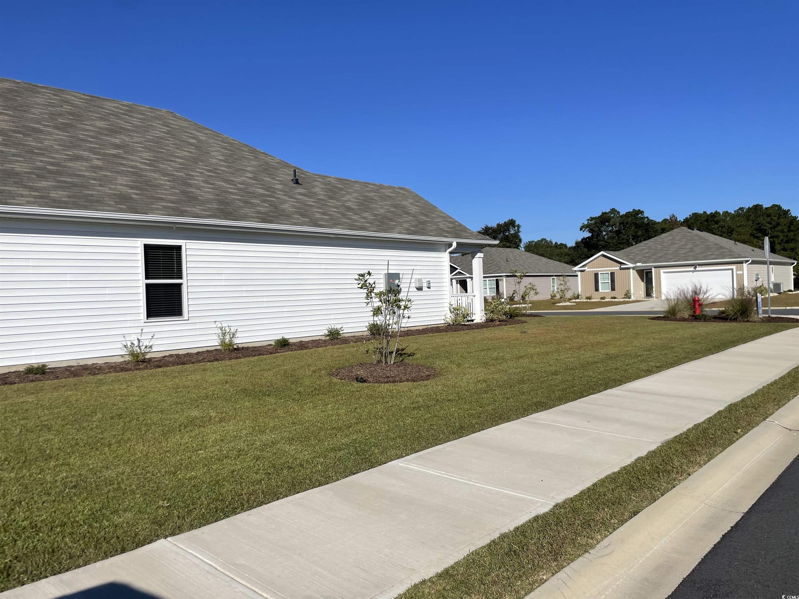 351 Jeff Waters Circle Longs, SC 29568 - Photo 30 of 33 View of side of home featuring a lawn, roof with shingles, and a garage