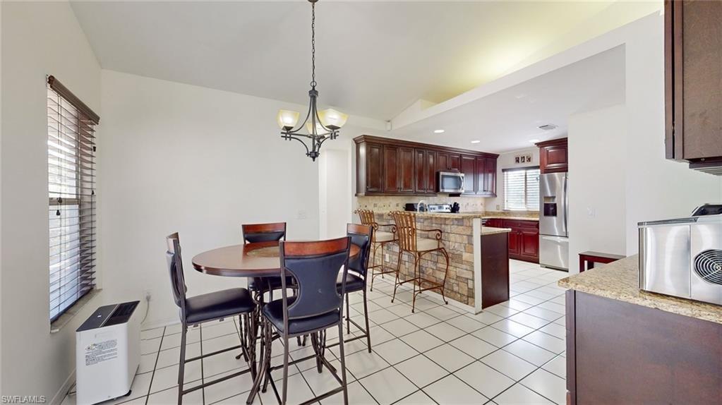 18249 Lee Road Fort Myers, FL 33967 - Photo 7 of 31 a view of a dining room with furniture a kitchen and chandelier
