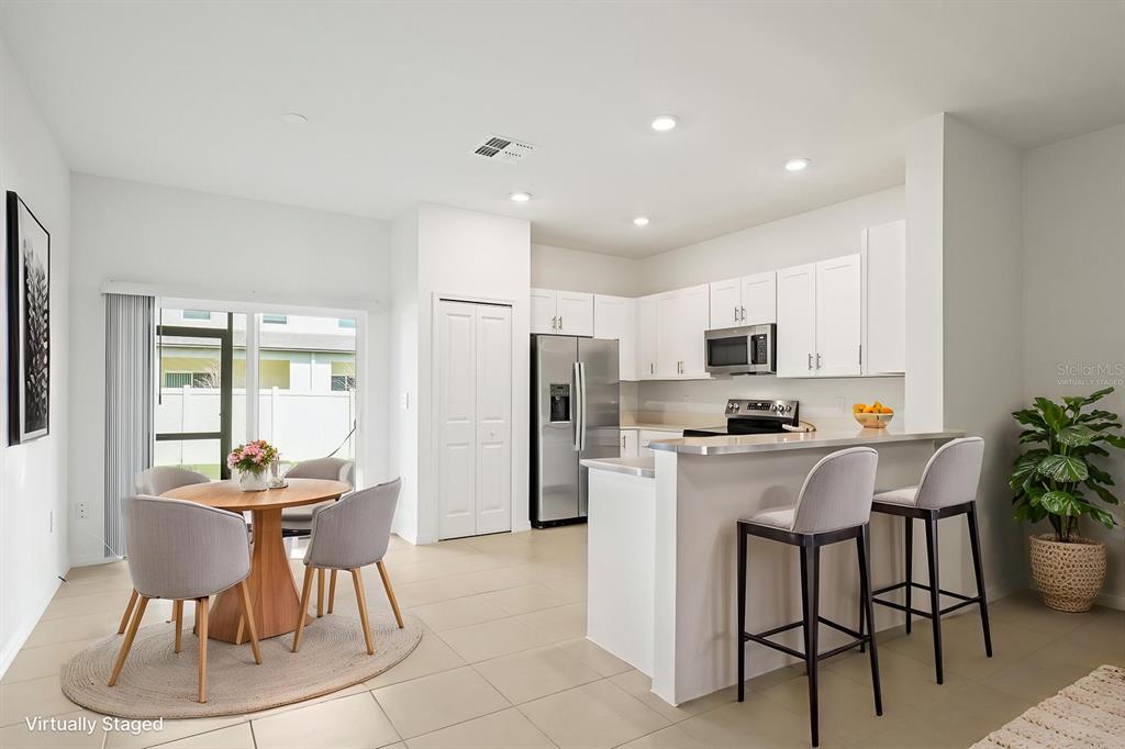 2642 Sunray Venus Way Ruskin, FL 33570 - Photo 7 of 30 a kitchen with stainless steel appliances kitchen island granite countertop a dining table chairs and a refrigerator