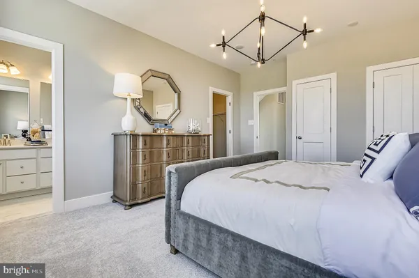 a bedroom with a bed a chandelier with a dresser