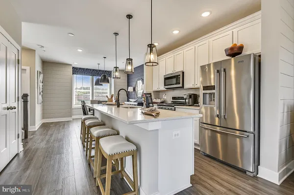 a kitchen with stainless steel appliances a refrigerator a sink dishwasher a stove and white cabinets with wooden floor