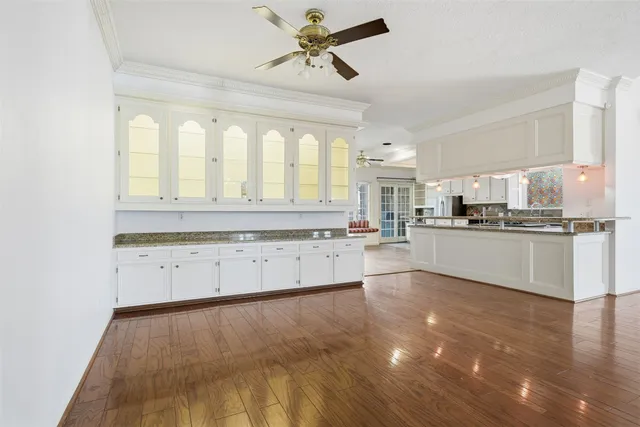 a large white kitchen with kitchen island a stove a sink dishwasher and white cabinets with wooden floor