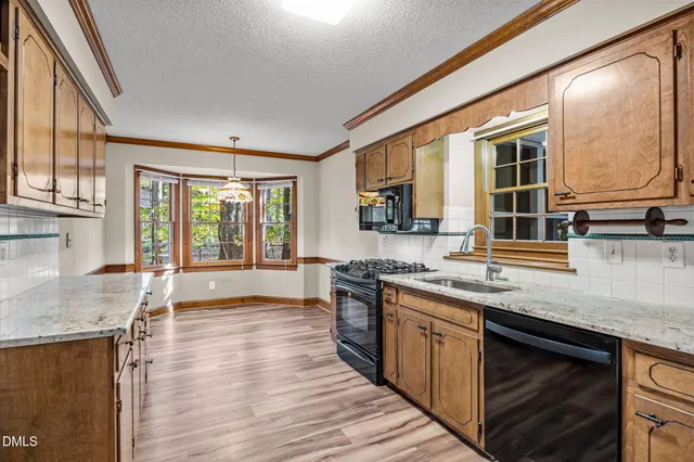a kitchen with stainless steel appliances granite countertop hardwood floor sink stove and wooden cabinets