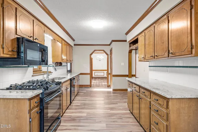 a open kitchen with stainless steel appliances granite countertop a stove a sink dishwasher and cabinets with wooden floor