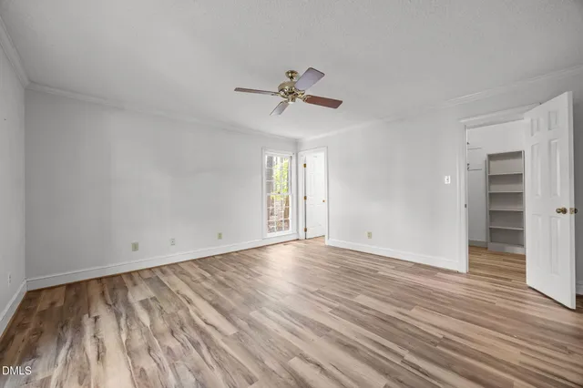 an empty room with wooden floor ceiling fan and windows