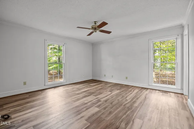 a view of empty room with wooden floor and fan