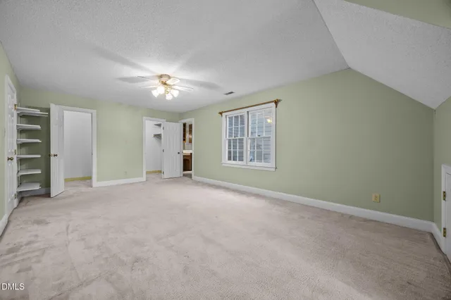 an empty room with closet and a ceiling fan