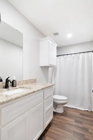 a bathroom with a granite countertop sink toilet and a mirror