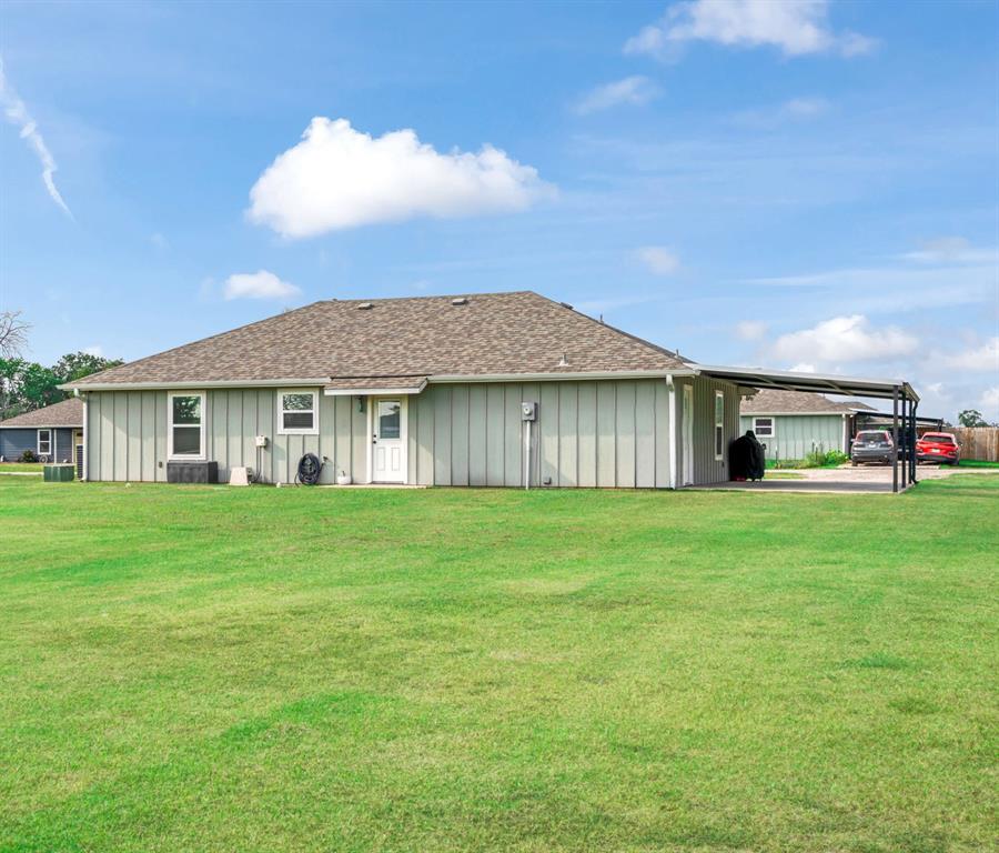 21 Private Road Paris, TX 75462 - Photo 15 of 15 Back of property with board and batten siding, roof with shingles, a lawn, and an attached carport