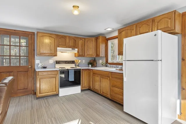 a kitchen with a refrigerator a stove top oven a sink and dishwasher with wooden floor