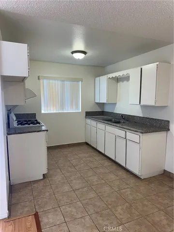 a kitchen with granite countertop a sink stove and cabinets