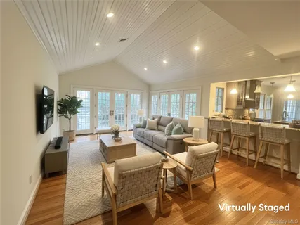 a living room with couches and kitchen view with wooden floor
