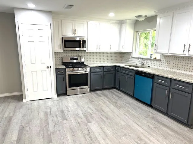 a kitchen with stainless steel appliances granite countertop a stove a sink and a microwave