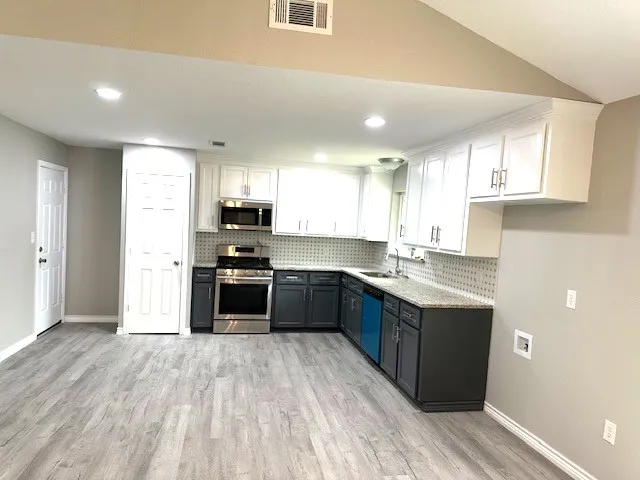 a kitchen with granite countertop a stove top oven sink and cabinets